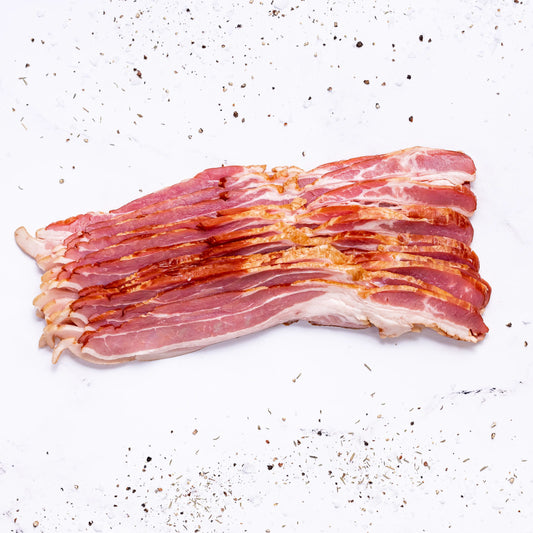 Several strips of Applewood Bacon are arranged neatly on a white surface, surrounded by scattered black pepper and seasoning.