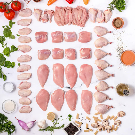 The Whole Chicken Box features various raw chicken cuts arranged on a white surface with herbs, vegetables, spices, cheese, and seasonings. Its 100% American, seed oil free, and contains no added hormones.